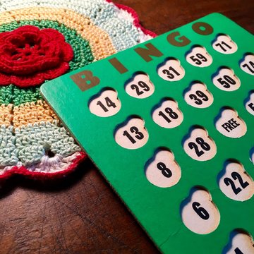 Vintage green bingo card and crocheted doily on wood table.
