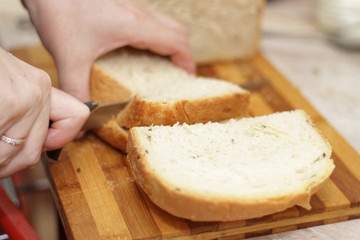 Woman cutting a bread on the wooden desk