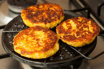 Traditional Colombian Arepa de Choclo Preparation : Corn breads being roasted on a round grill