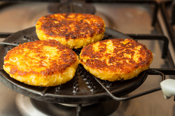 Traditional Colombian Arepa de Choclo Preparation : Corn breads being roasted on a round grill