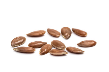 Close up of some linseeds on white background seen obliquely from above with focus on the closest