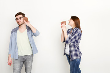 Young casual couple talking through tin can phone