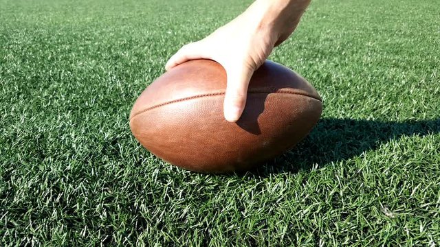 Close-up of a man's hand takes and lies a ball for American football.