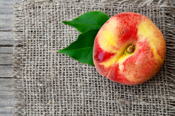 Chinese flat donut peach with leaves on on burlap napkin.Donut peache also known as Saturn...