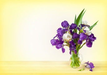 bouquet of irises in a vase on a wooden table. Space for text