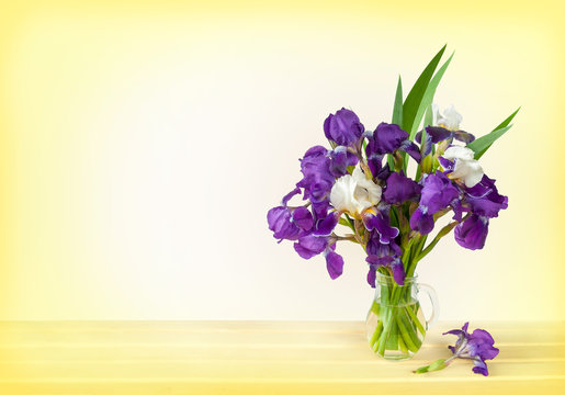 bouquet of irises in a vase on a wooden table. Space for text