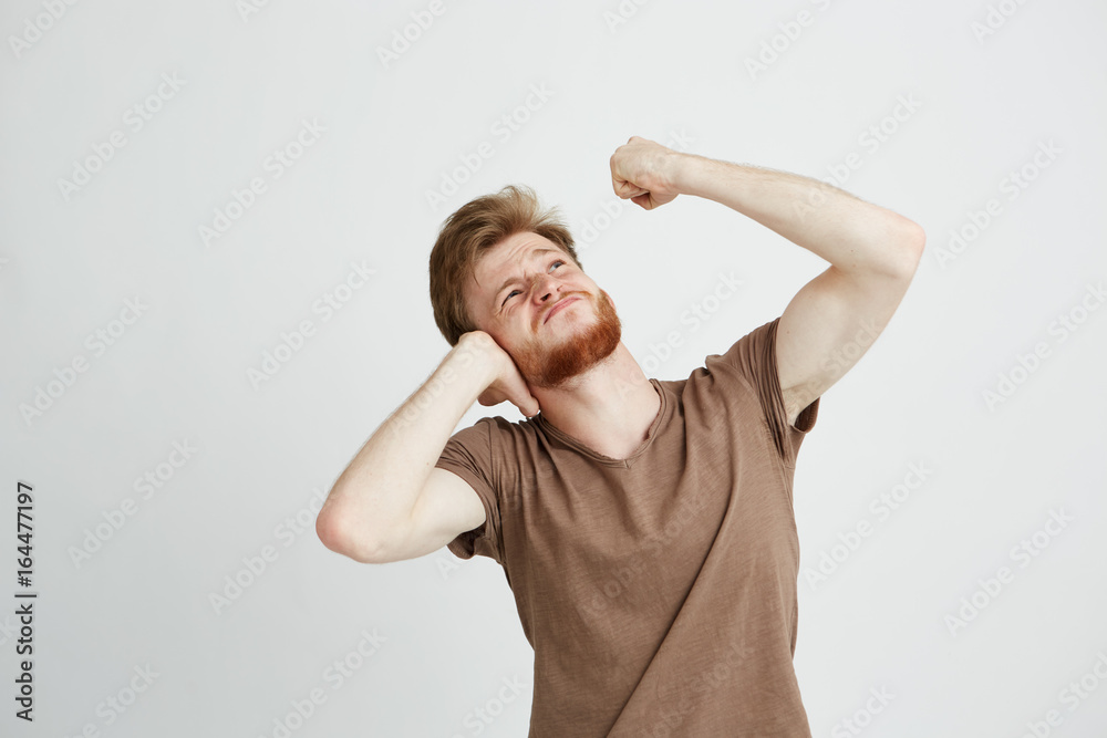 Canvas Prints Portrait of young angry man with beard closing ears looking up showing fist over white background.