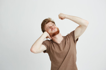Portrait of young angry man with beard closing ears looking up showing fist over white background.