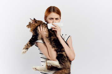 Beautiful young woman on white isolated background holds a cat, an allergy