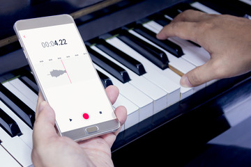 Mobile phone is recording the sound of man playing piano