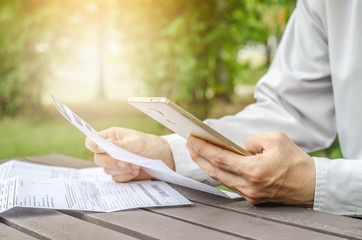Businessman with bills and smart phone at the table. Calculation of costs