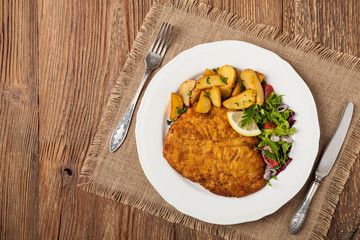 Chicken schnitzel, served with roasted potatoes and salad.