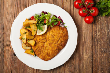 Chicken schnitzel, served with roasted potatoes and salad.
