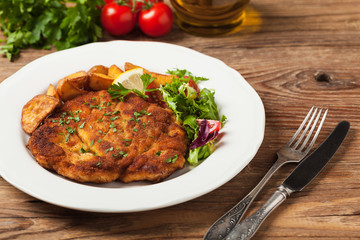 Chicken schnitzel, served with roasted potatoes and salad.