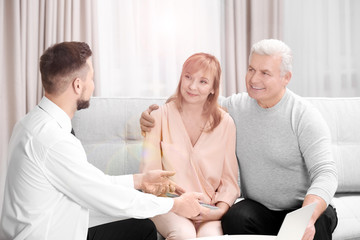 Obraz premium Middle aged couple signing contract sitting on couch at home