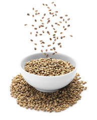 Hemp seeds falling into bowl on white background. Superfood concept