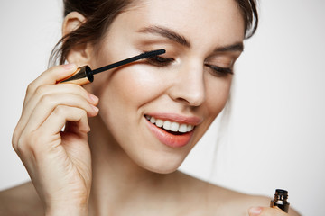 Fototapeta premium Cute beautiful girl dye eyelashes smiling over white background. Beauty health and cosmetology concept.