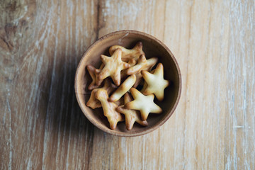 Top view image of small biscuits in many shapes in wooden cup on wood table background