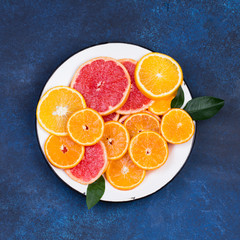 Fresh oranges, grapefruits and madarine slices on dark stone background.