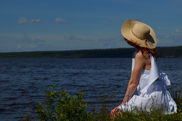 Fototapeta premium Woman in white dress and hat relax on riverside