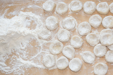 Pieces of dough in flour on a wooden board