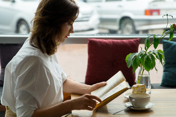 Girl reading book and relaxing in the cafe. girl in business clothes resting during the lunch break
