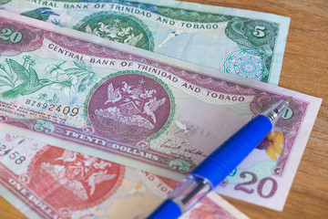 Trinidad and Tobago dollars with pen for calculations