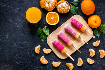 Orange juice, oranges, mandarins and citrus ice cream on black table background top view copyspace