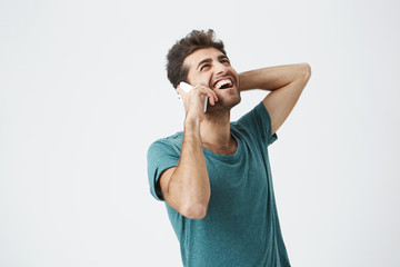 Happy young man feeling excited, happy and laughing while talking on the phone. Stylish hipster...