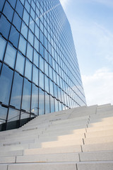 View on the modern office skyscraper facade and concrete stairs with blue sky