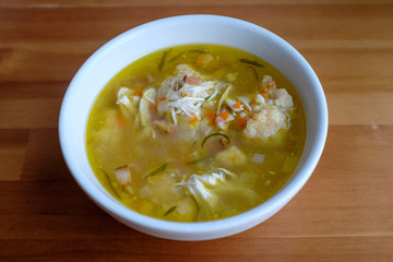 Homemade chicken and dumpling soup on a wooden table.