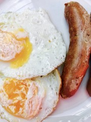 Breakfast fried eggs with sauasage served on a white plate 