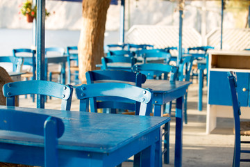 Fototapeta na wymiar Tables and chairs in a street restaurant in Kamari on Santorini
