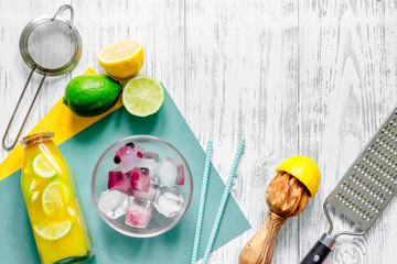Making lemonade. Cookware, fruits, bottle of lemonade and ice cubes on wooden table background top view copyspace