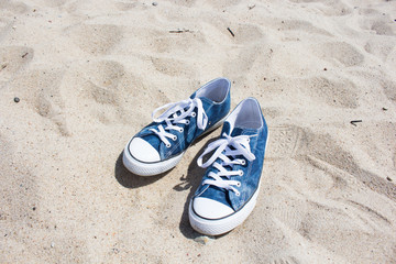 Fototapeta na wymiar blue sneakers on white sand