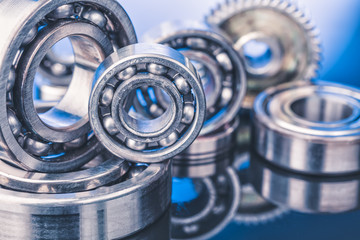 Group of various ball bearings close up on nice blue background with reflections