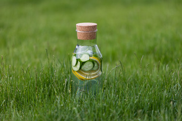 A glass decanter with a summer refreshing lemonade made of lemons and cucumber with mint added on a...