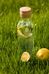 A glass decanter with a summer refreshing lemonade made of lemons and cucumber with mint added on a...