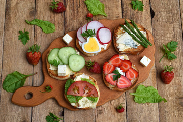 Set of healthy whole wheat bread sandwiches with fuits, vegetables, cheese and leafy green herbs on picnic wooden table. Ciabatta sandwich bar or buffet. Top view. Making lunch time snacks concept