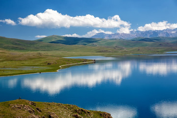 Mountain Song Kol lake. Beautiful clouds reflected in water. Kyrgyzstan.