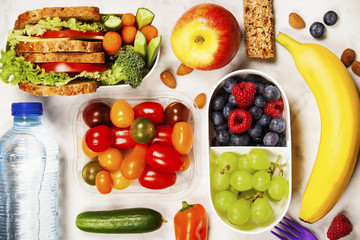 Healthy lunch box with sandwich and fresh vegetables, bottle of water and fruits