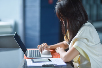 Young pretty business woman with laptop in the office, smiling pretty young business woman in glasses sitting on workplace. Selective focus