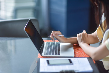 Young pretty business woman with laptop in the office, smiling pretty young business woman in glasses sitting on workplace. Selective focus