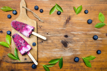 Obraz na płótnie Canvas Tasty homemade blueberries ice cream on wooden background. Organic fruit popsicles.