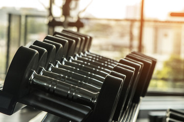 Healthy lifestyle fitness concept with rows of dumbbells and in the gym and a personal trainer for lifestyle concept for muscle building, strength, and weight loss with high contrast and monochrome.