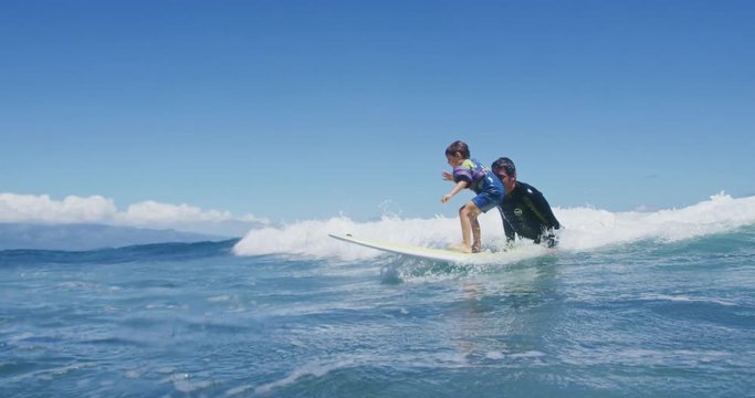Father teaching son to surf tandem surfing