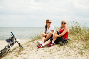 Fototapeta premium Women resting after riding bike on the beach 