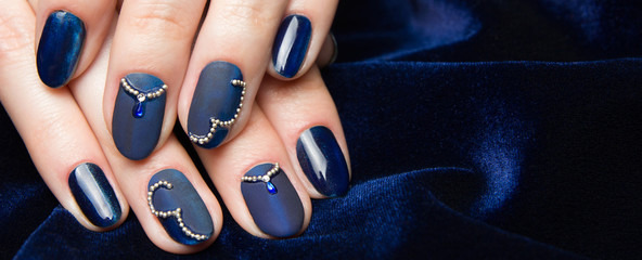 French manicure - beautiful manicured female hands with blue manicure with rhinestones on dark blue...