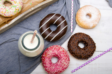 Bottle of milk and colorful donuts with chocolate and icing, selective focus