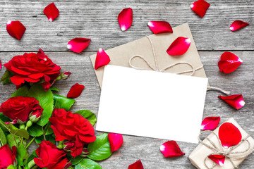 blank white greeting card and envelope with red roses flowers, petals and gift box